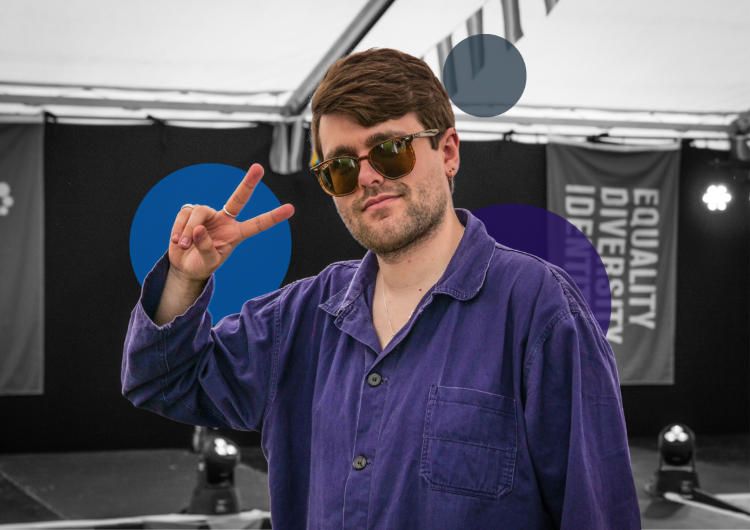 Young person in sunglasses and purple shirt making a peace sign at an outdoor METRO event, standing confidently in front of branded banners.